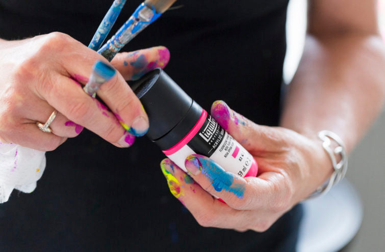 Acrylic Gouache şişesi tutan sanatçının boyalı elleri